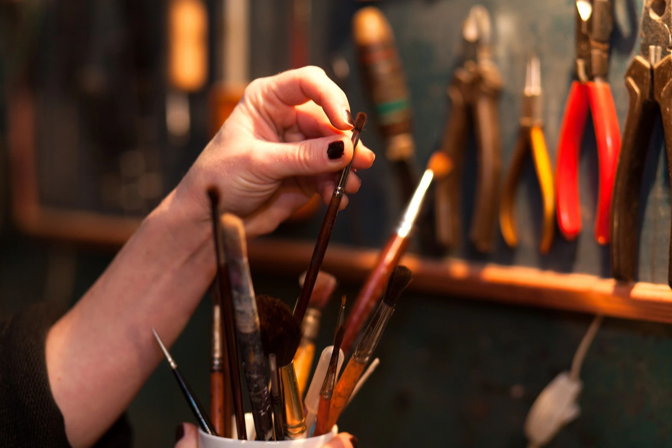 Hand selecting paintbrush from container