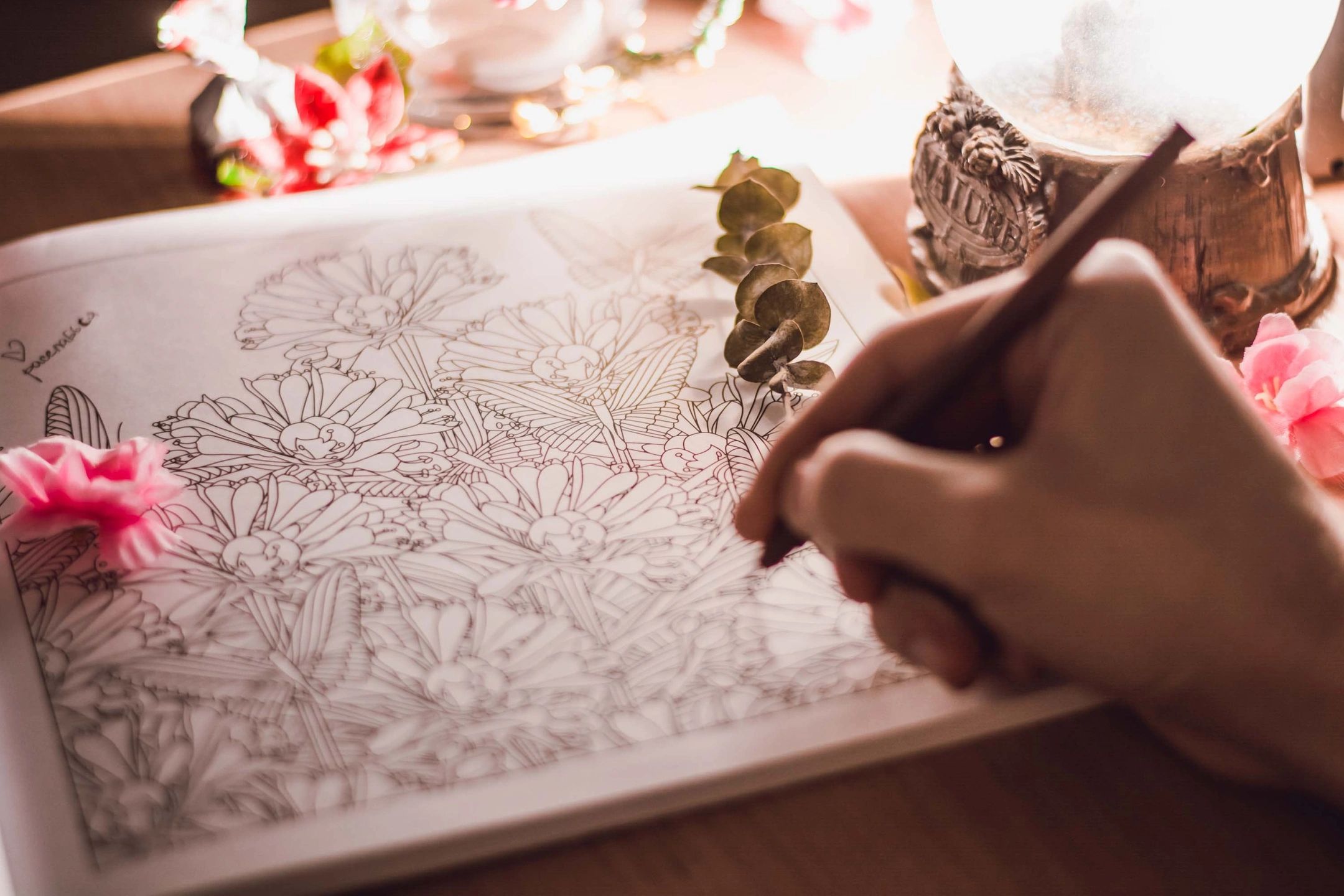 Artist drawing intricate floral line art surrounded by fresh flowers